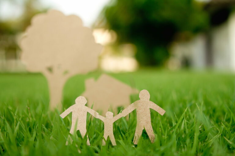 Figures familiales en carton découpées, assises sur l'herbe